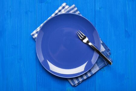 Blue plate with fork on napkin and blue tableの写真素材