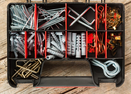 Assortment of nails, hooks, plugs and picture hangers in opened plastic case, high angle view