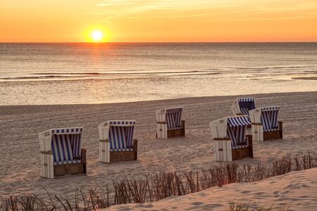 Beach chairs at North Sea beach of Hornum, Sylt, in sunsetの写真素材