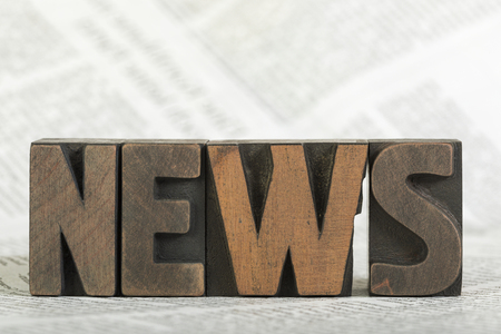 News, word written with vintage wooden letterpress printing blocks on newspaper, shallow depth of fieldの写真素材