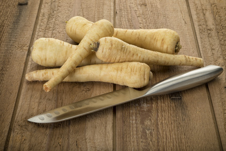 Parsnips roots and chefs knife on rustic wooden backgroundの写真素材