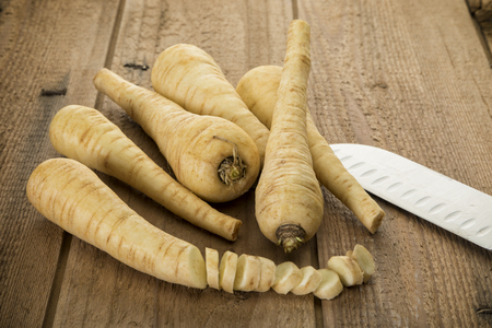Parsnips roots and slices with chefs knife on rustic wooden backgroundの写真素材