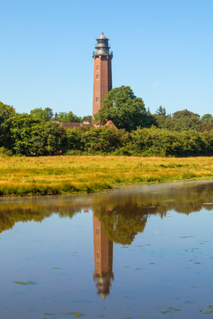 Lighthouse Neuland at Behrensdorf on the Baltic Sea coast reflected in a pondのeditorial素材