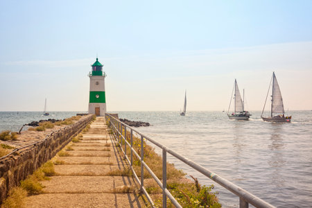 Lighthouse of SchleimÃ¼nde between baltic Sea and Schlei inlet on a bright sunny day, sail boats passing byのeditorial素材