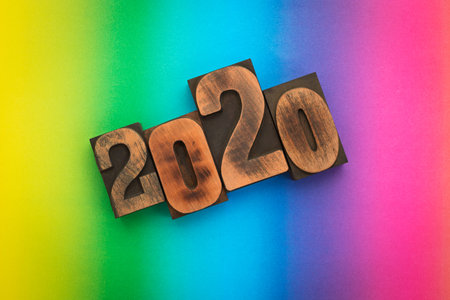 Year 2020 written with vintage letterpress printing blocks on  rainbow colored background