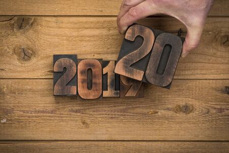 Change from 2019 to 2020. Hand replacing vintage letterpress number printing blocks on rustic wood backgroundの写真素材