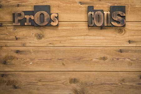 Pros and Cons set with vintage letterpress type on rustic wood planks background, copy space belowの写真素材