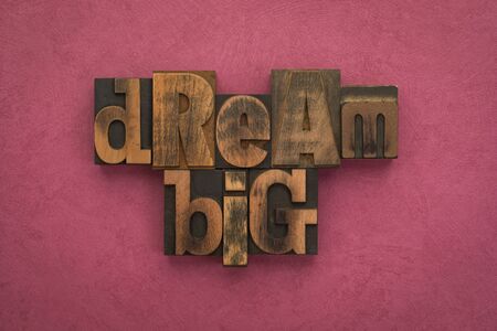 Dream big, phrase written with vintage letterpress printing blocks on textured pink background.の写真素材