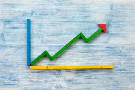 Line graph made of building blocks on blue wooden background flat layの写真素材