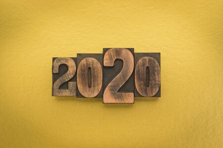 Year 2020 written with vintage letterpress printing blocks on gold colored backgroundの写真素材