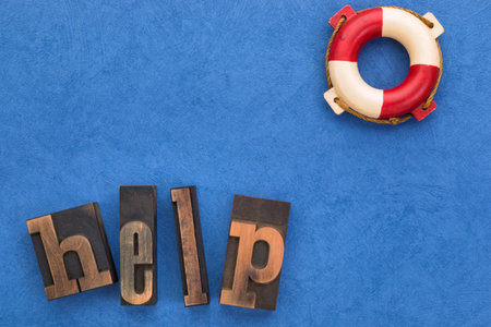 Support concept. Word help set with vintage letterpress type and life buoy on textured blue...