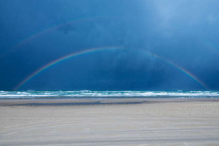 Full rainbow over beach and North Sea at LÃ¸kken, Denmarkの写真素材