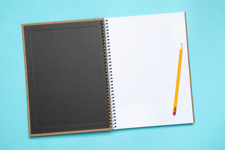 Flat lay opened blank squared notebook with yellow pencil high angle view with copy space
