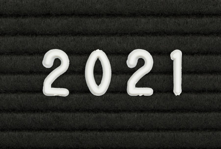 Year 2021 written with white plastic numbers on black felt message board closeup