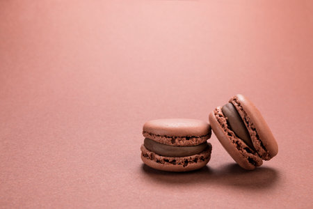 Chocolate flavor French macaron cookies closeup on background of a similar brown color with copy spaceの写真素材