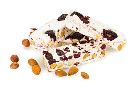Heap of turron blocks with berry fruits, almonds and hazelnuts isolated on white backgroundの写真素材