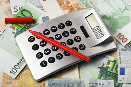 Desktop calculator and red pen on european currency backgroundの写真素材