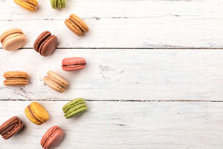 Rustic wooden background with a variety of colorful macarons pastry, French cookies high angle view with copy spaceの写真素材