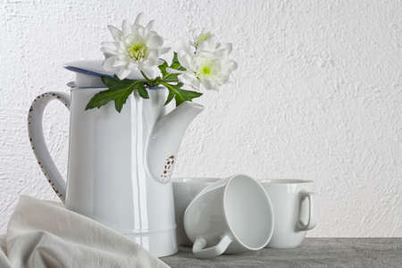 White still-life with Dahlias in old coffee pot, coffee cups and clothの写真素材