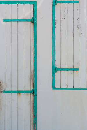 Background with closeup of turquoise and gray painted wooden door and shutterの写真素材
