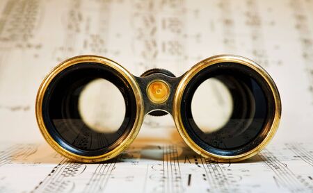 Old theater binoculars over classical music scores.の写真素材