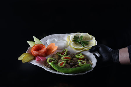 Hand Holding Liver Meatballs Serving Plate - Isolated on Black Background - Food Imagesの写真素材