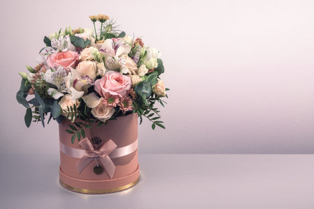 A beautiful bouquet of tender flowers of pink roses, white lilies, and yellow gerberas in a...