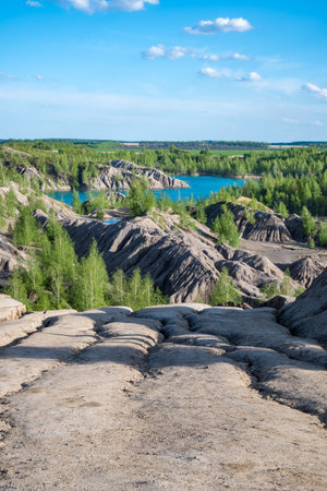 Scenic quarry lake with eroded steep slopes in the foreground and green trees in the background....