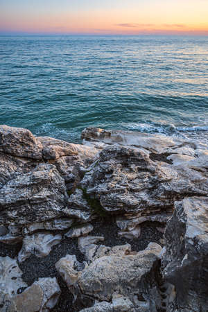 Colorful seaside sunset landscape with white stones in the foreground and red sky in the background. Summer leisure activity, tourism, travel, vacation, scenic destinations.の写真素材