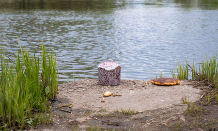Easter cake and a pancake on the concrete plate riverside grown with green grass in springtime. Traditions, Orthodox Church, outdoors holidays, faith, religion.の写真素材