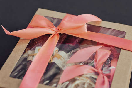 Cardboard gift box tied with a red ribbon on a black background.の写真素材