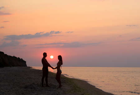man and woman holding hands on the beach at sunriseの写真素材