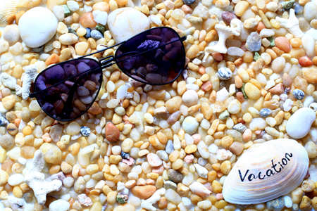 beach vacation - pebbles, sea shells and sunglassesの写真素材