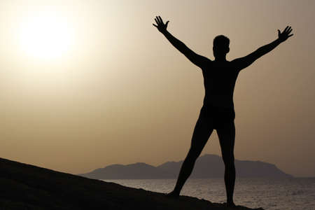 silhouette of a man doing yoga excercises on the beach at sunriseの写真素材
