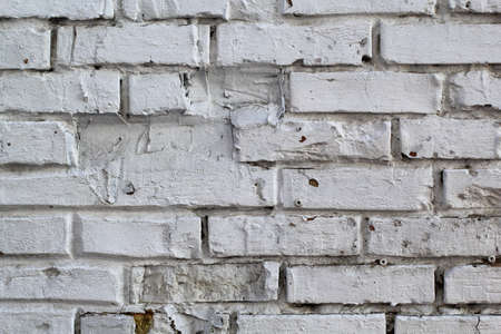 white brick wall with uneven and missing stones for backgroundの写真素材