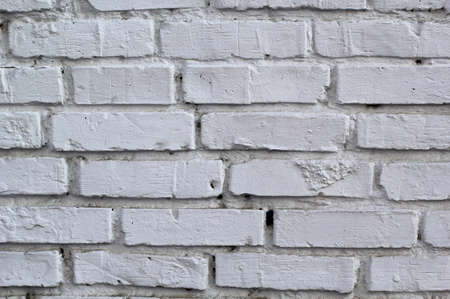 white brick wall with uneven and missing stones for backgroundの写真素材