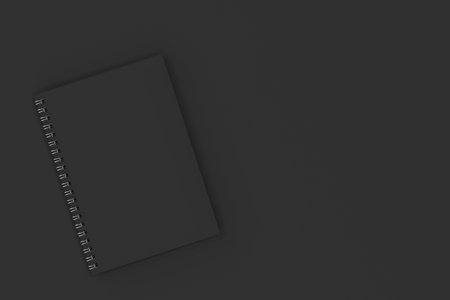 Closed blank notebook with black cover and metal spiral bound on black background. Business or...
