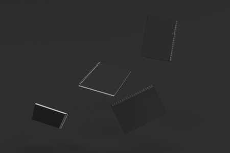 Four blank notebooks with black covers and metal spiral bound on black background. Business or education mockup. 3D rendering illustrationの写真素材