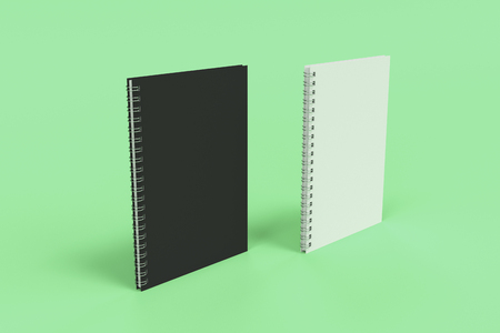 Two blank notebooks with black and white covers and metal spiral bound on green background. Business or education mockup. 3D rendering illustrationの写真素材