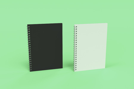 Two blank notebooks with black and white covers and metal spiral bound on green background. Business or education mockup. 3D rendering illustrationの写真素材