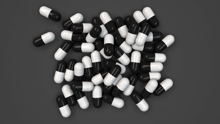 Pile of black and white medicine capsules on black background. Medical, healthcare or pharmacy...