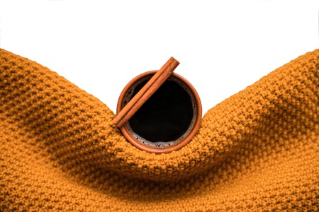 Clay cup of coffee with cinnamon wrapped in an mustard scarf on a white isolated background. Winter or autumn concept. Flat lay, top view, copy space.の写真素材