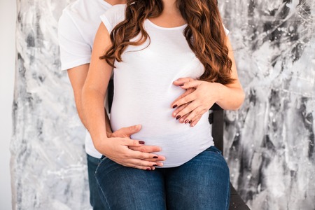 Happy parents hug and hold pregnant belly. Concept of care and baby waiting.の写真素材