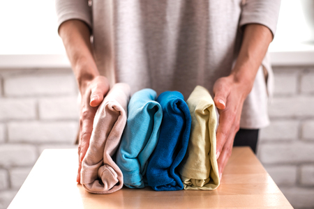 Housewife neatly folds a stack of clothes on the wooden background. Concept of housekeeping.の写真素材