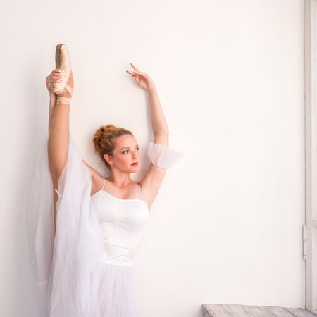 Young graceful ballerina dancing on white studio. Beautiful dancer is training.の写真素材