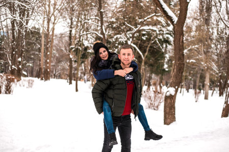 Happy couple have fun in winter park. They are walking and playing with each other. Concept of...
