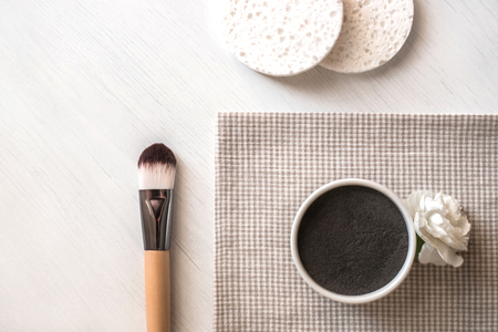 Preparing natural cosmetic facial mask in ceramic bowl on white wooden background with brush and flower. Rustic style.の写真素材