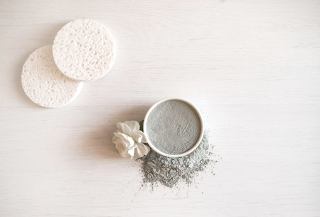Blue cosmetic clay with white carnation and sponges on white wooden background. Top view.の写真素材