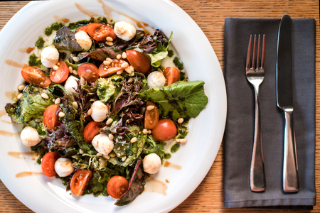Fresh salad made of vegetables and greenery on wooden background. Table served for one in restaurant or cafe.の写真素材