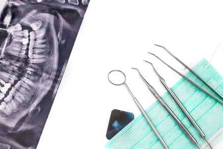 Dentist tools on mask and x-ray photo isolated on white background. Flat lay.の写真素材